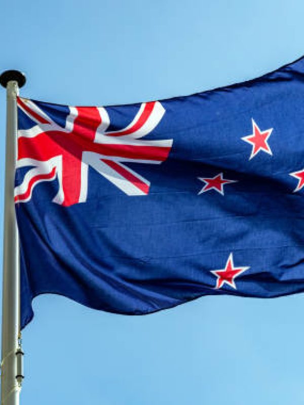New Zealand flag, New Zealand national symbol waving against clear blue sky, sunny day